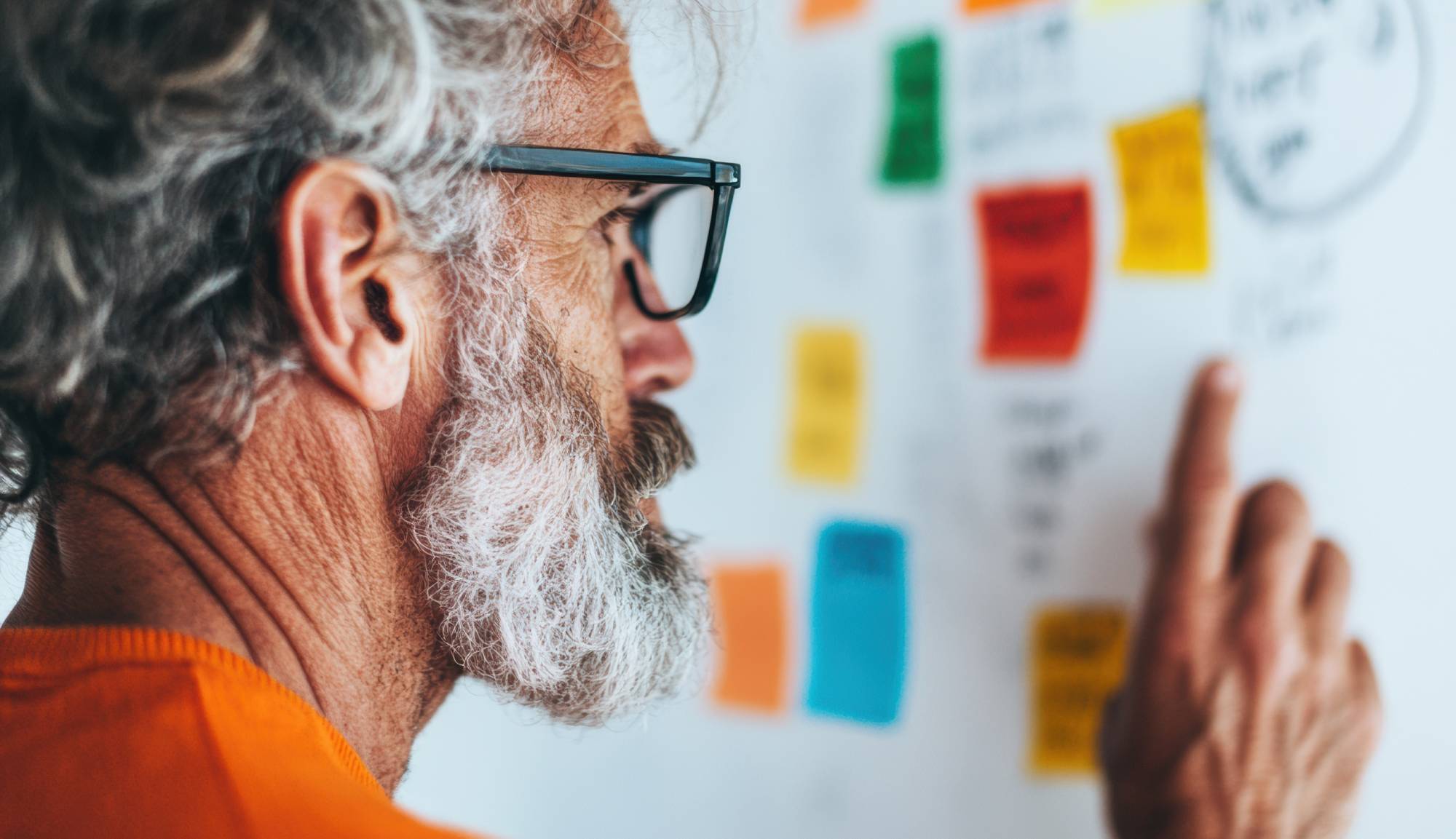 Man looking at whiteboard with post it notes